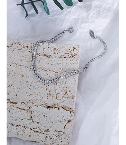 Macro detail of silver double-layered tennis bracelet with zircon inlay and K18 tag