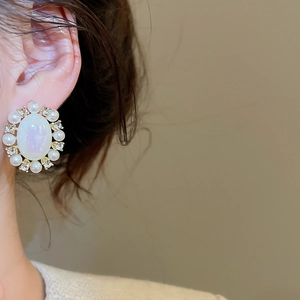 Detail shot of vintage oval opal earring with pearls and crystals on female model ear