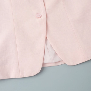 Détail d'un gilet rose clair avec boutons de qualité et coutures parfaitement finies