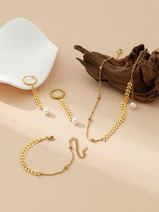Détail de l'ensemble collier et bracelet feuilles dorées avec perles sur plat en céramique