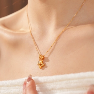 Detail of gold hollow clover pendant with sparkling zircon on a delicate cable chain