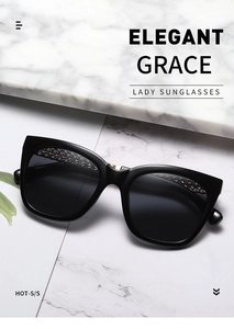 Detail of black cat eye sunglasses featuring gold metal chain inlay on the frame top