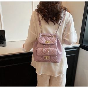 Detail of light purple quilted backpack showing golden twist lock and chain strap on model