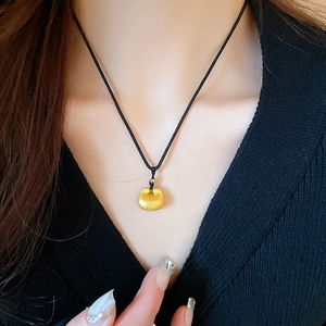 Detailaufnahme von goldenem Fu-Anhänger an schwarzer Kordelkette an Model