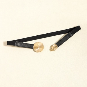 Detailed macro view of black elastic belt with gold sunburst engraved metal buckles