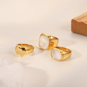 Detailed view of three vintage gold rings with white shell inlays on wooden background