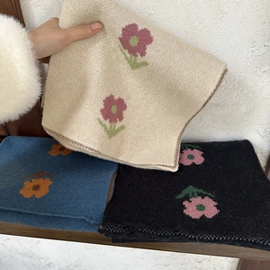 Close-up of knit floral scarves in beige, blue, and black with soft cashmere texture