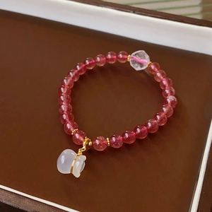 Detail of beaded crystal bracelet with pink strawberry quartz and a white jade money bag charm