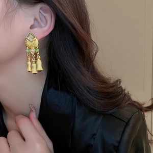 Vintage gold tassel earrings with green gemstones and pearls shown on a model side view