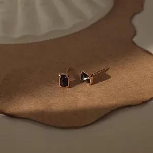 Detail of square gold studs with black stone inlay on a vintage textured surface