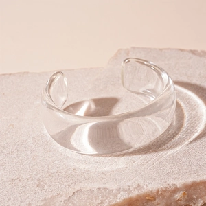 Detailansicht eines transparenten geometrischen Acryl-Armreifs auf Naturstein