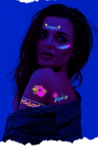 Detail of neon UV glow temporary tattoos with floral patterns on skin under blacklight