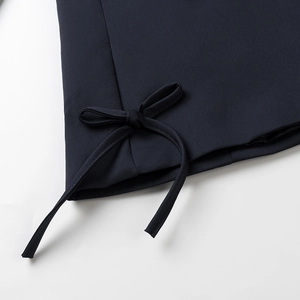 Detail of navy blue blazer featuring a structured woven fabric and stylish bow tie-up hem