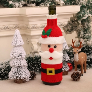 Close-up of a knitted Christmas wine bottle cover with Santa suit design and plush trim