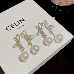 Detail of elegant bow earrings with crystal pavé and large white pearls in gold and silver