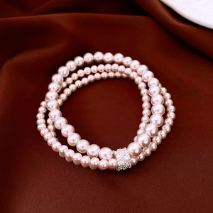 Détail macro du bracelet perles à trois rangs avec fermoir strass sur soie brune