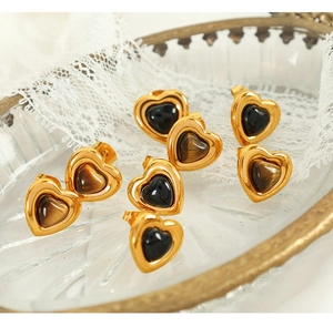 Detailed view of heart-shaped tiger eye and black stone earrings on lace fabric