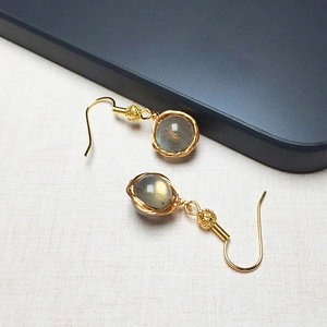 Détail macro de boucles d'oreilles en or 14K avec labradorite grise sur lin