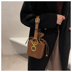 Close-up of brown leather bucket bag featuring metal ring buckle and adjustable strap