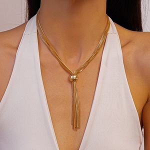Détail d'un collier à chaînes dorées avec un pendentif sphérique poli et de longs glands