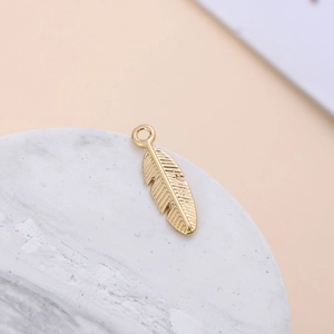 Detailed macro view of a golden feather alloy pendant on white marble background
