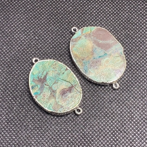 Detalle del conector de ágata oceánica irregular con borde plateado y bucles dobles