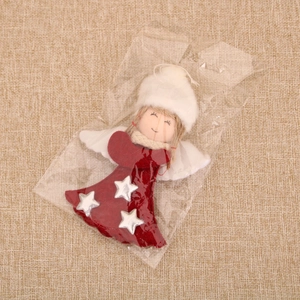 Detailed view of a Christmas angel ornament with red sequins and white wings in packaging