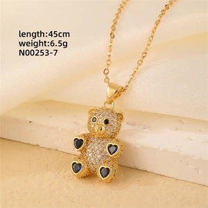 Close-up of gold teddy bear pendant with micro-pave zircons and blue heart accents
