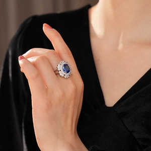 Dettaglio ravvicinato di un anello vintage con zaffiro ovale e halo di diamanti sul dito