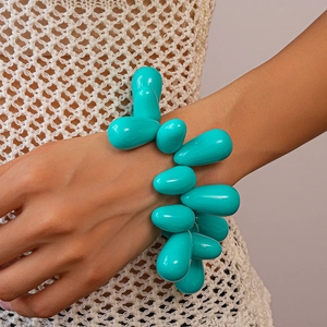 Detail of bright blue acrylic teardrop charms on a statement bracelet worn on the wrist