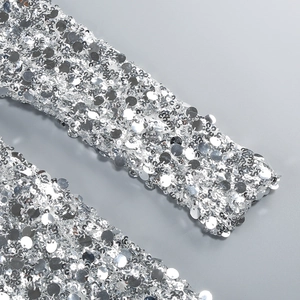 Macro shot of shimmering silver sequins on the long sleeve party dress fabric