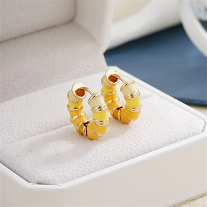 Macro view of gradient orange enamel hoop earrings with gold metal rings in a box