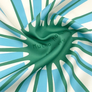 Detail view of premium silk square scarf with green geometric patterns and logo