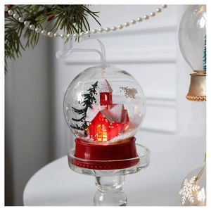 Detail of a glowing Christmas ornament with a red house and green tree inside