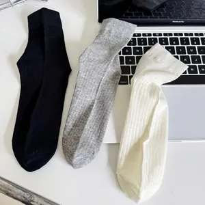 Three pairs of ribbed cotton mid-calf socks in white, grey, and black colors