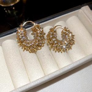 Close-up of gold U-shaped earrings with spiral sparkling rhinestones in a display box