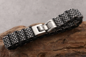 Detailed close-up of men's braided leather and stainless steel bracelet with fold-over clasp