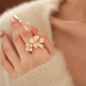 Close-up of a double flower open ring with white enamel petals on a gold-plated band