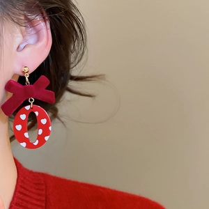 Gros plan sur les boucles d'oreilles nœud velours rouge avec motifs cœurs blancs