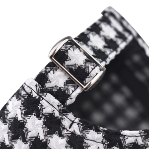 Close-up of adjustable silver metal buckle and black and white houndstooth plaid fabric