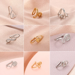 Diverse U-vormige niet-piercing neusmanchetten in goud en zilver op roze zijden stof