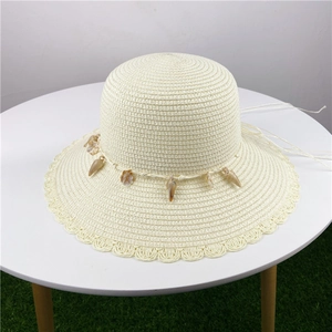 Close-up of woven straw hat featuring shell decorations and wavy brim detail