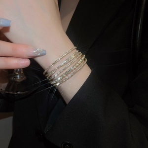 Macro detail of multi-layered gold bracelet with zircon pavé setting on a model's wrist