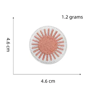 Detail of a 4.6cm sunburst embroidered patch in rose gold and white colors