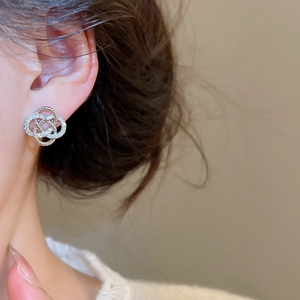 Gros plan d'une boucle d'oreille fleur en argent avec zircon sur une oreille