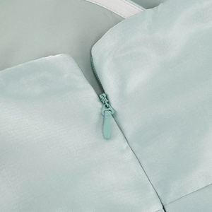 Detailed macro view showing the hidden zipper closure on the light green woven dress