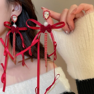 Gros plan de boucles d'oreilles à nœud élégant avec pompons rouges et perles blanches