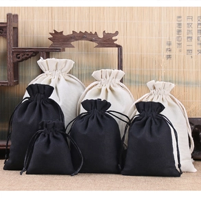 Various sizes of linen drawstring jewelry pouches arranged on a classic wooden shelf