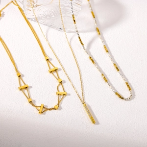 Three minimalist gold and silver necklaces featuring geometric pendants on white stone