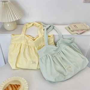 Detail of pleated canvas tote bag with adjustable knotted shoulder straps in pastel colors